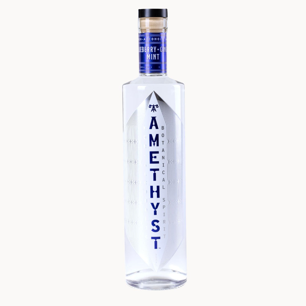 A clear glass bottle of Amethyst Mint vodka with a blue label and black cap, centered on a light off-white background.