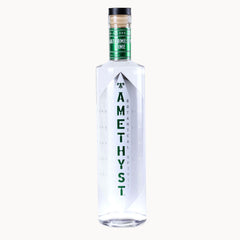 A clear glass bottle of Amethyst Watermelon Lime with a black cap, green neck label, and green vertical text on the front, set against a plain off-white background.