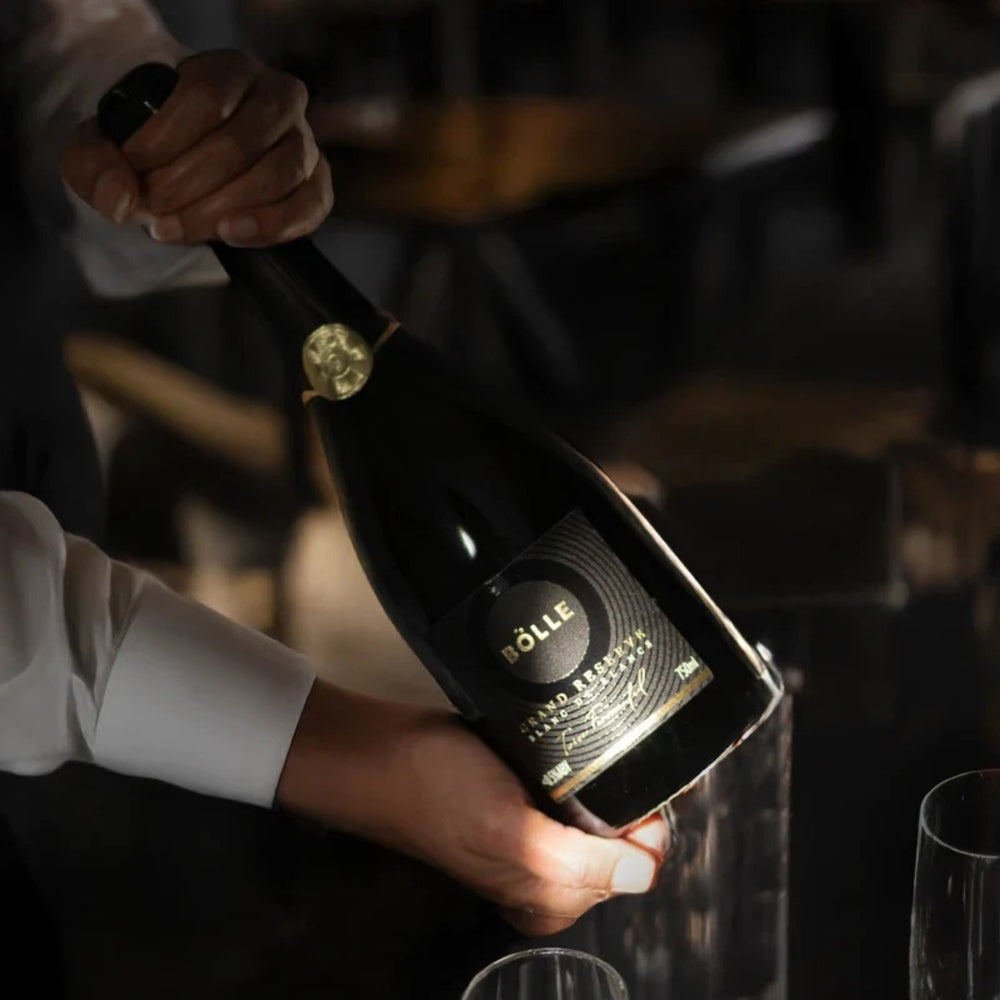 A bottle of Bölle Grand Reserve sparkling wine, featuring a dark glass bottle with a gold seal and gold lettering on the label, set against a plain white background.