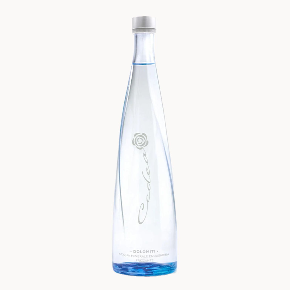 A tall, slender clear glass bottle of Cedea Doloniti water with a white cap, featuring a silver rose logo and elegant cursive script on a clean white background.