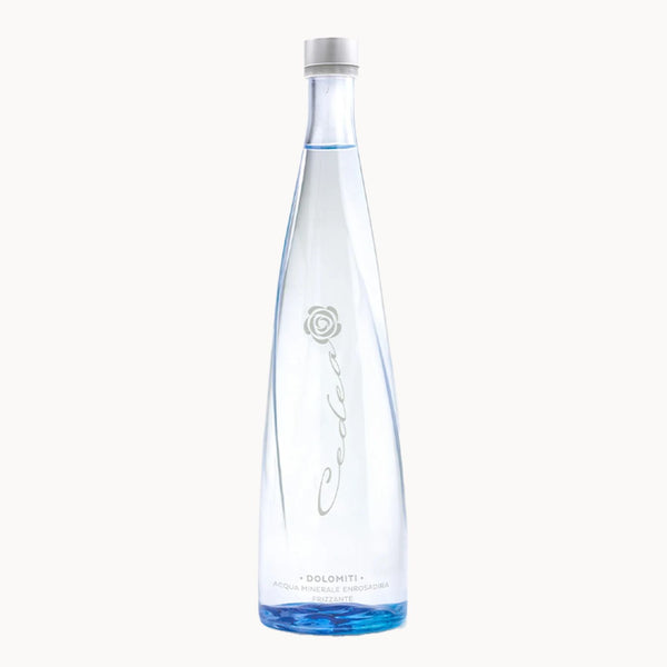 A tall, slender clear glass bottle of Cedea Doloniti water with a white cap, featuring a silver rose logo and elegant cursive script on a clean white background.