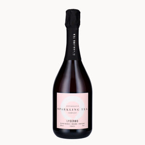 A bottle of Lyserød Copenhagen Sparkling Tea Company sparkling tea, featuring a pale pink label and a black foil-wrapped neck, set against a solid off-white background.