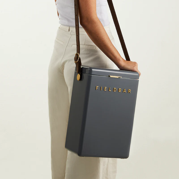 Person holding a gray cooler bag with 'FIELDBAR' branding on a light background