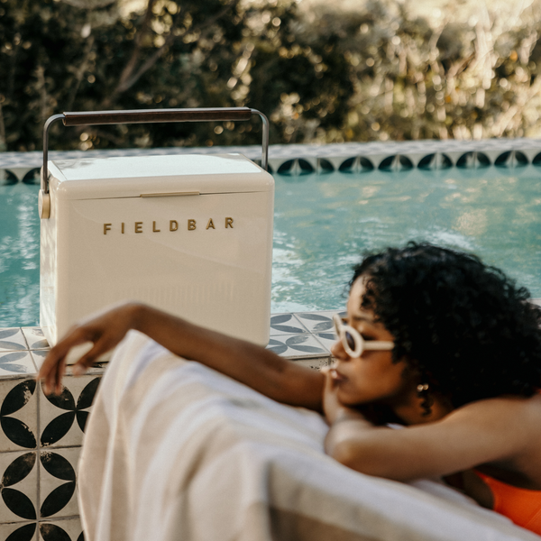 Person lounging by a pool with a Fieldbar cooler