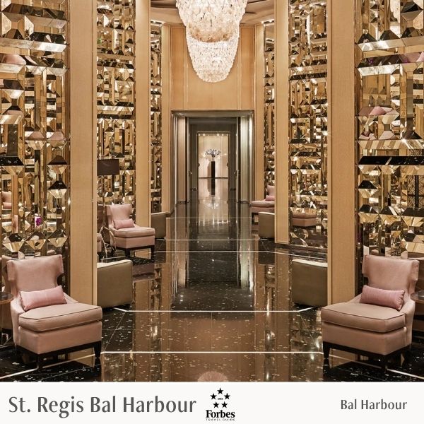 Luxurious interior of a hotel lobby with reflective floor and mirrored walls, featuring 'St. Regis Bal Harbour' and Forbes logos.