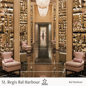 Luxurious interior of a hotel lobby with reflective floor and mirrored walls, featuring 'St. Regis Bal Harbour' and Forbes logos.