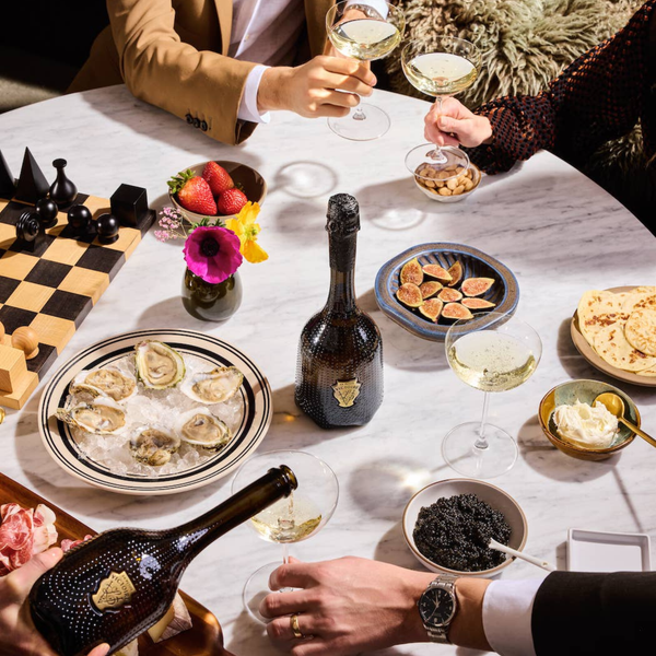 Rienne and La Petite Victoire being enjoyed by people having a meal with oysters, champagne, and snacks at a table.