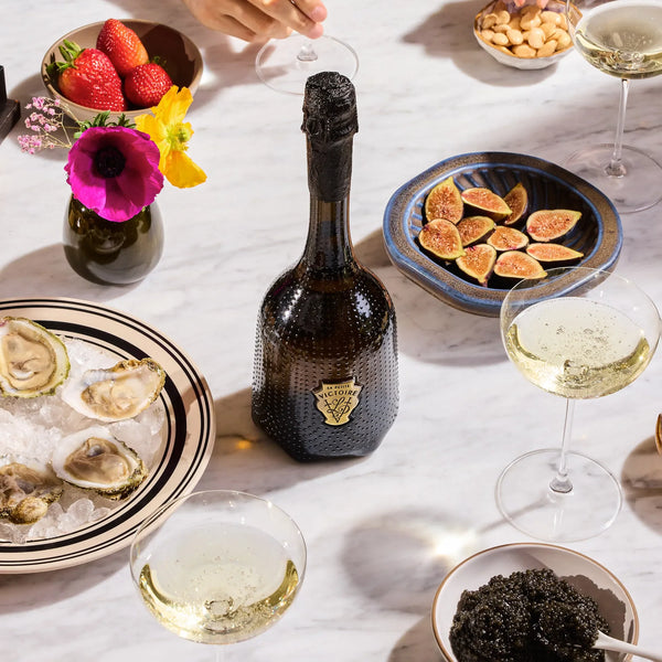 Rienne & La Petite Victoire being enjoyed at a table setting with oysters, figs, and caviar on a white tablecloth.