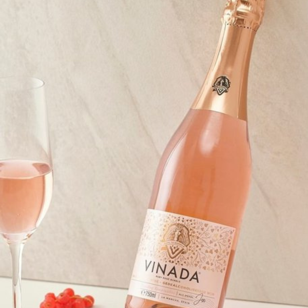 Rienne_Vinada_Bottle of Vinada rose wine with a glass and berries on a light background
