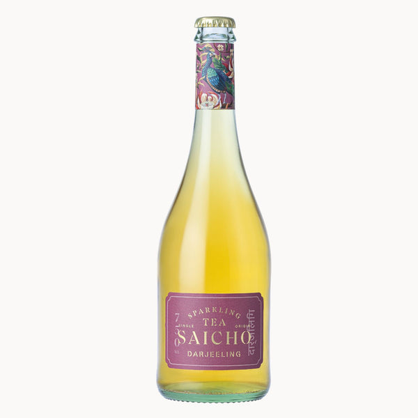 A bottle of Saicho Sparkling Tea Darjeeling on a clean white background. The glass bottle contains a pale golden-yellow liquid and features a purple label with white text, topped with a decorative purple neck label showing a peacock illustration.